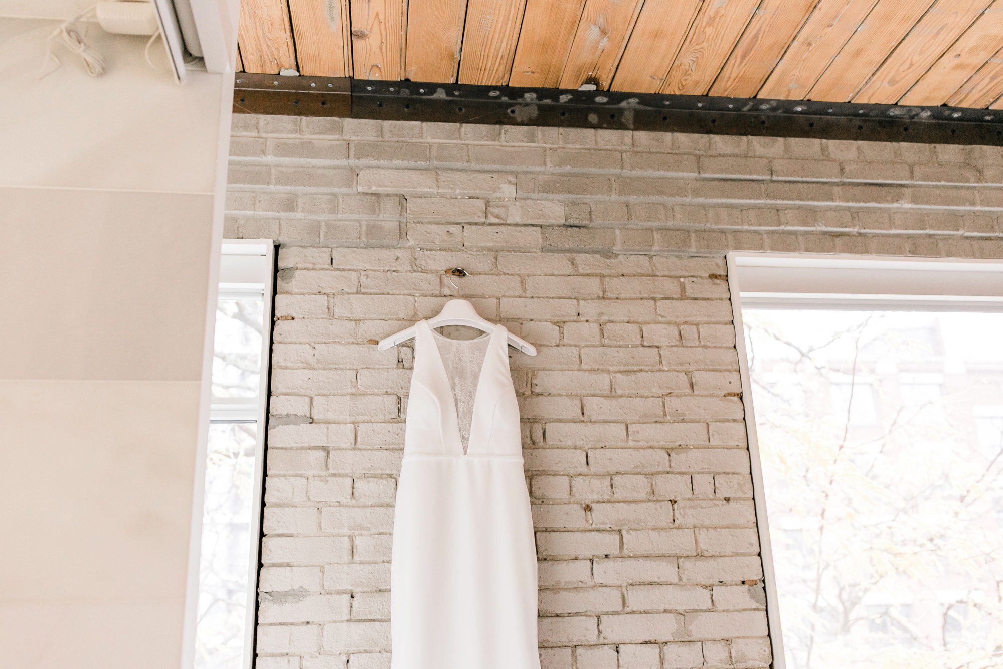 brides dress hanging on brick wall