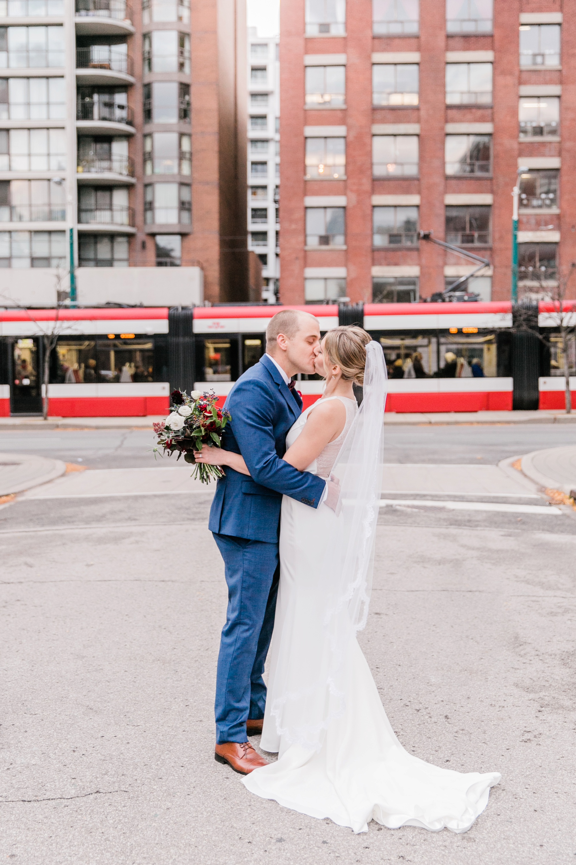 bride and groom kiss with streetcar in back